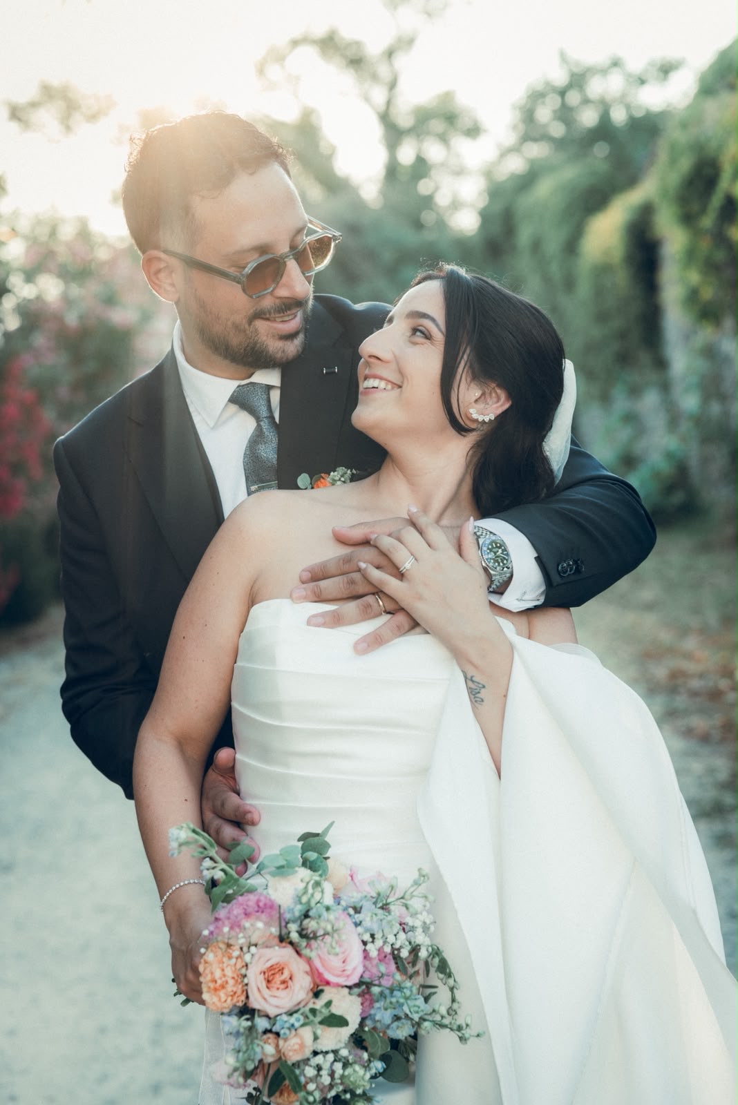 Les mariés enlacés, souriants, au coucher du soleil